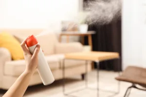 spraying air freshener in room