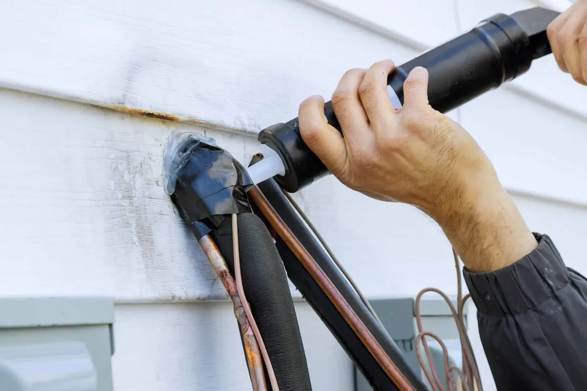 technician sealing exterior wall entry point with caulking to prevent pests entering home